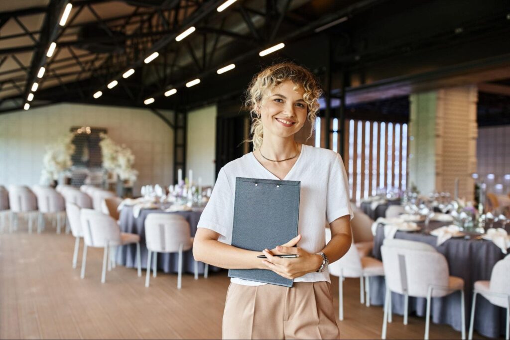 Hospitality Industry Woman Standing in Banquet Hall Holding Portfolio
